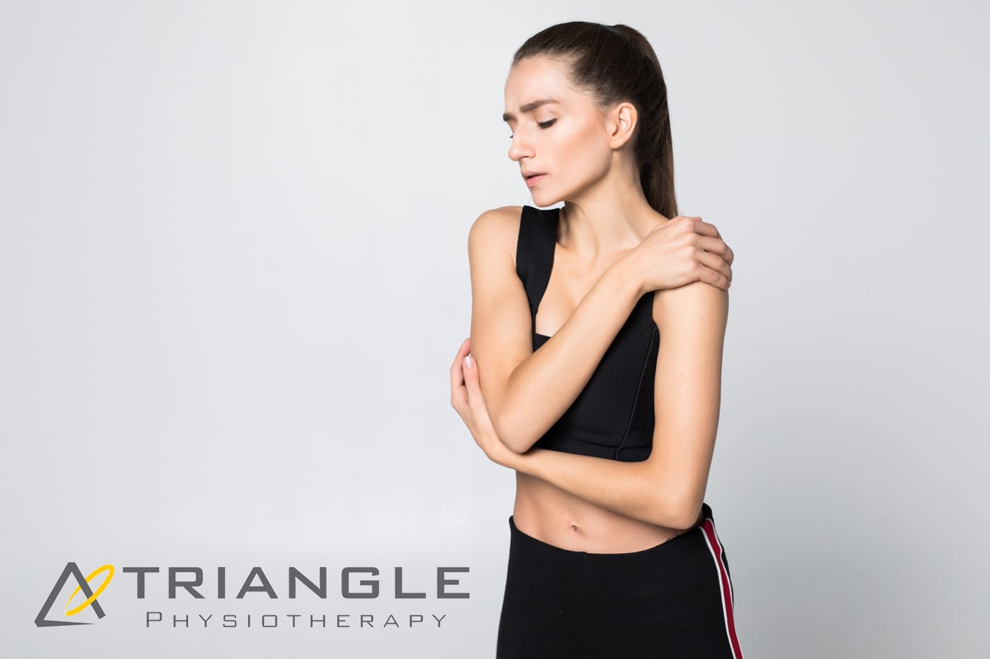 Upset brunette young woman injured arm during sport training, touches her wrist isolated on white background